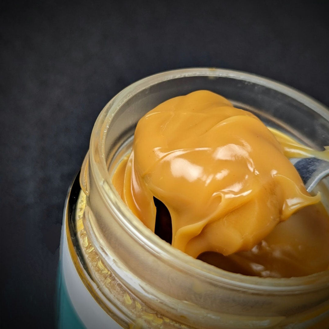 Spoon dipped into open jar of Crwst Award Winning Salted Caramel made with the best spiced rum from Barti Spiced Rum.